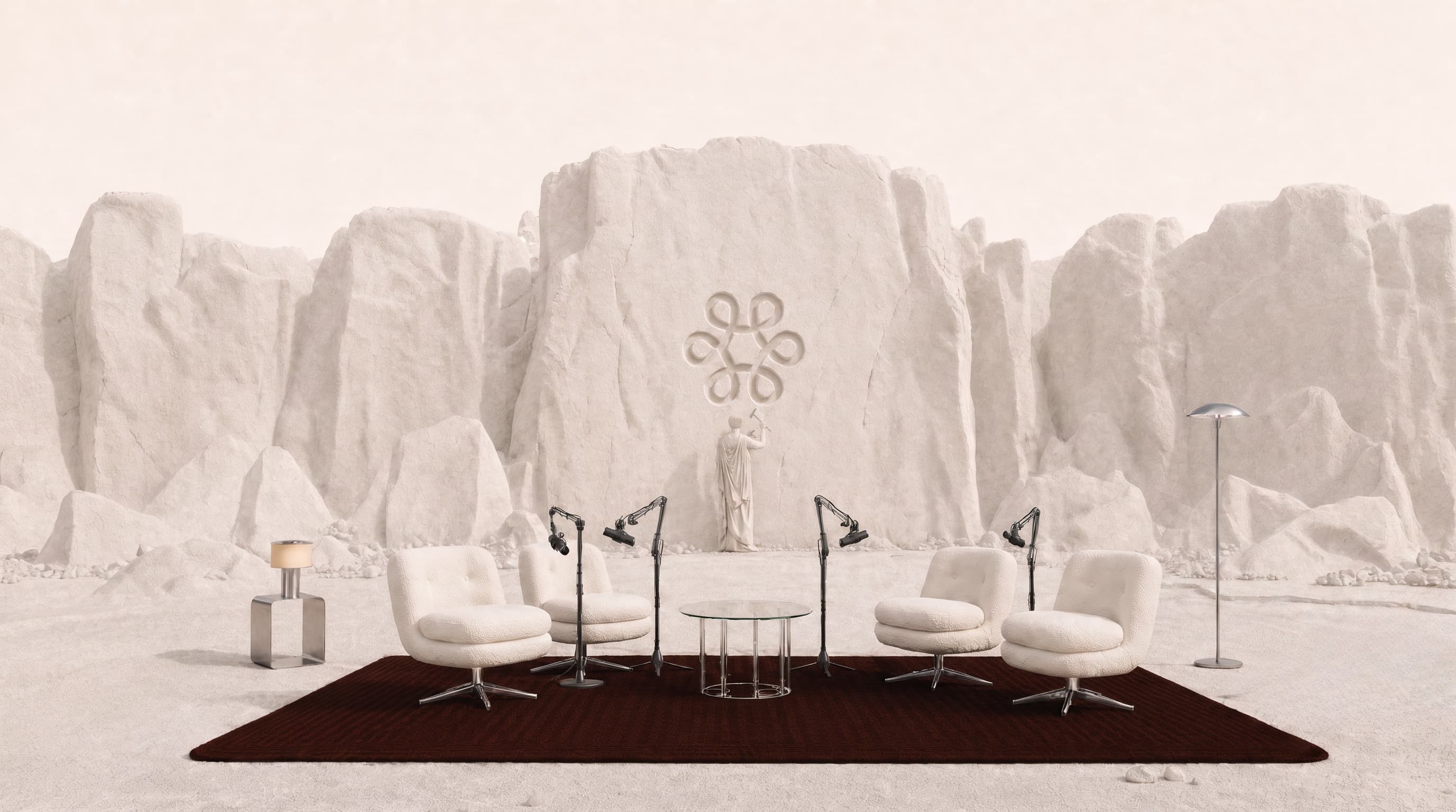Four cream armchairs and microphones in a white sculptural landscape beneath a deep red sky.
